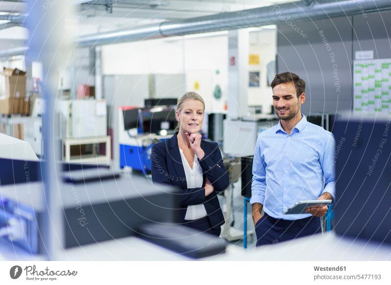 Smiling professional colleagues discussing while looking at machinery in illuminated factory color image colour image indoors indoor shot indoor shots interior