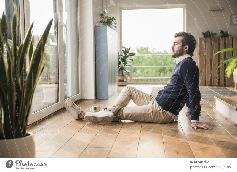 Young man sitting on floor, looking out of window, relaxing Businessman Business man Businessmen Business men getting away from it all Getting Away From All