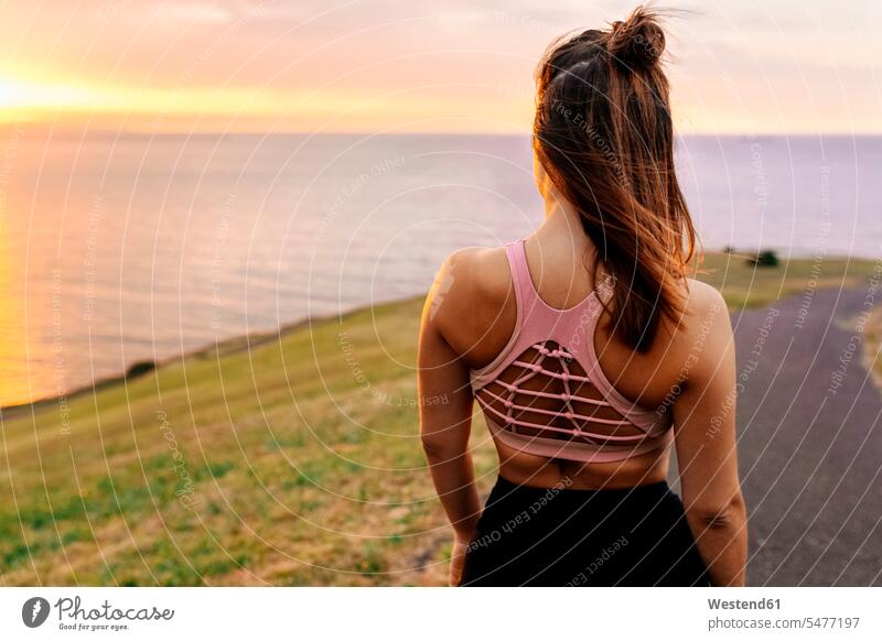 Young female athlete looking at sea during sunset color image colour image outdoors location shots outdoor shot outdoor shots rear view back view