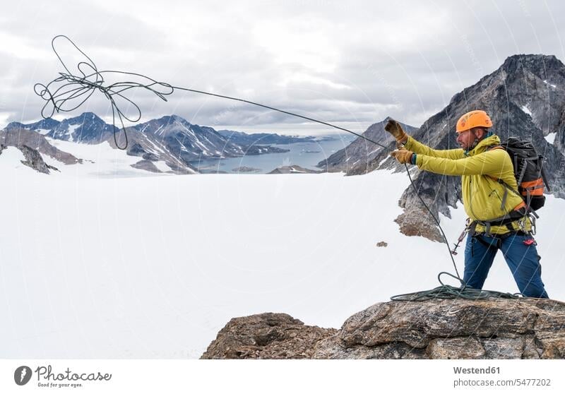 Greenland, Sermersooq, Kulusuk, Schweizerland Alps, mountaineer on summit throwing rope mountains ropes climber alpinists climbers Mountain Climber mountaineers