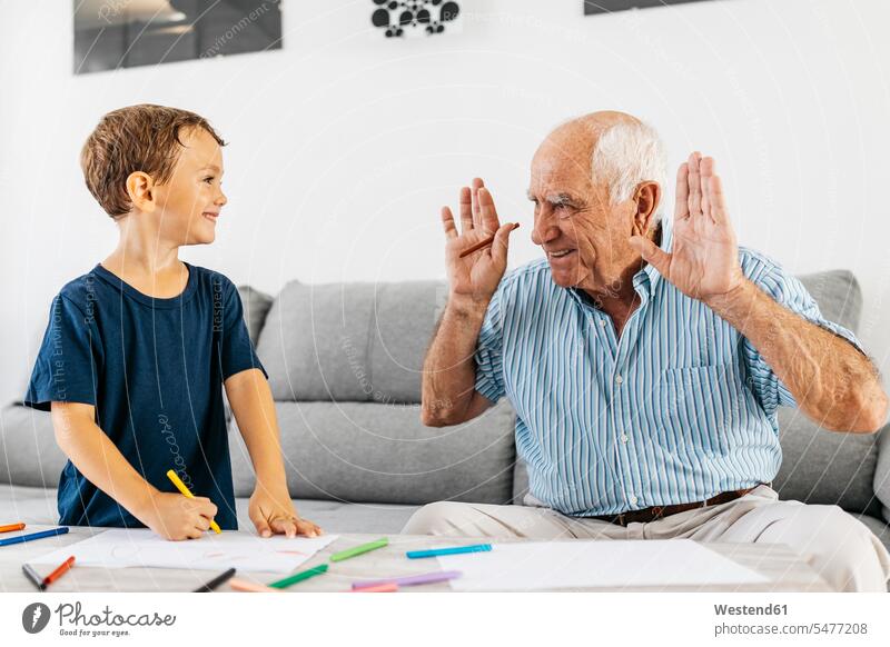 Grandfather and grandson drawing with coloured pencils at home grandfather grandpas granddads grandfathers grandsons sketching grandparents family families