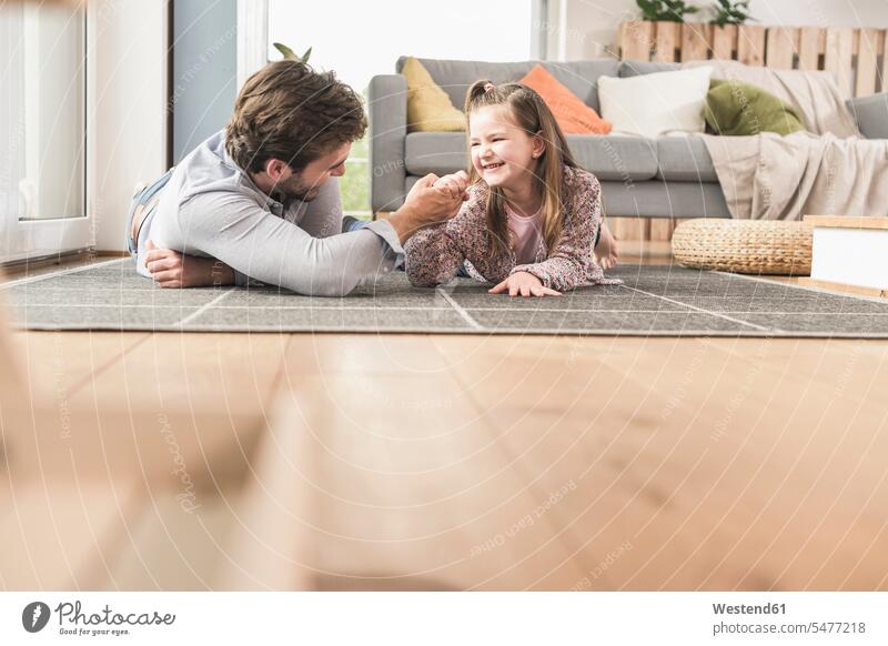Young man and little girl lying on ground, arm wrestling caucasian caucasian ethnicity caucasian appearance european laying down lie lying down floor floors
