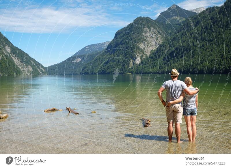 Germany, Bavaria, Koenigssee, couple standing in lake Konigssee arm in arm recreation relaxing Recreational water's edge waterside shore vastness wide Broad Far