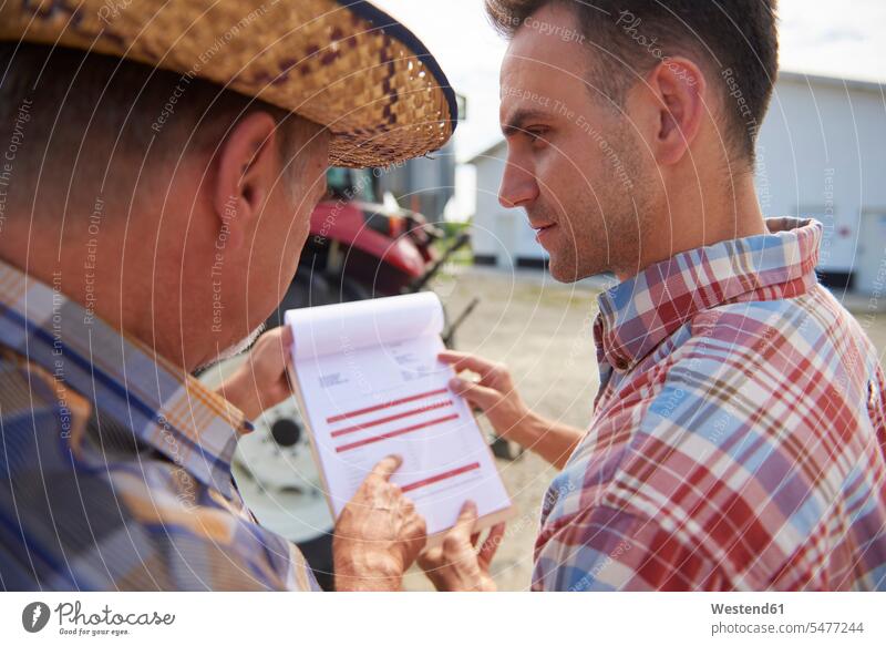 Two farmers analyzing data from clipboard on the farm clipboards clip-board clip-boards clip board agriculturists analysing agriculture rural scene