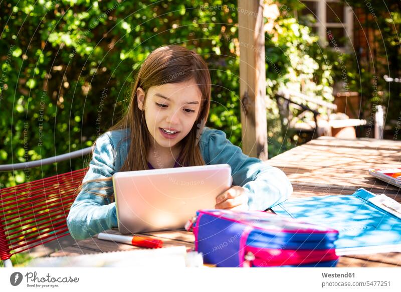 Girl sitting at garden table doing homework and using tablet human human being human beings humans person persons caucasian appearance caucasian ethnicity
