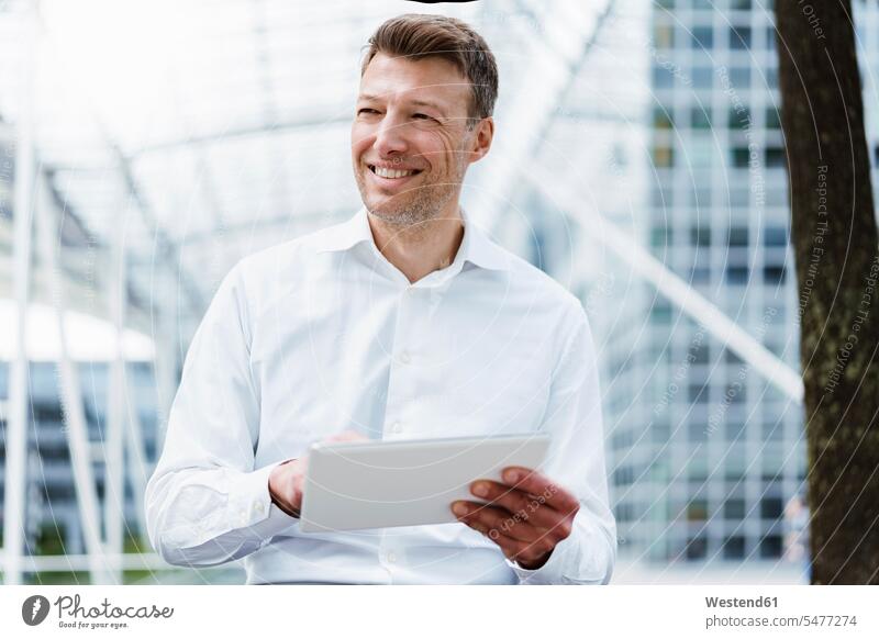 Smiling businessman with tablet outside in the city appointment date appointments dates dating confidence confident building buildings mobile working