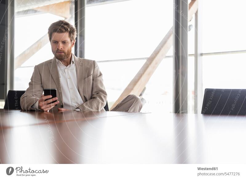 Businessman using cell phone in conference room Business man Businessmen Business men office offices office room office rooms meeting room conference rooms