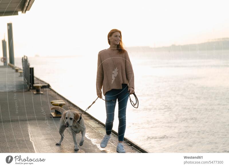 Germany, Hamburg, woman walking with dog on pier at the Elbe shore females women piers riverside riverbank happiness happy smiling smile going dogs Canine