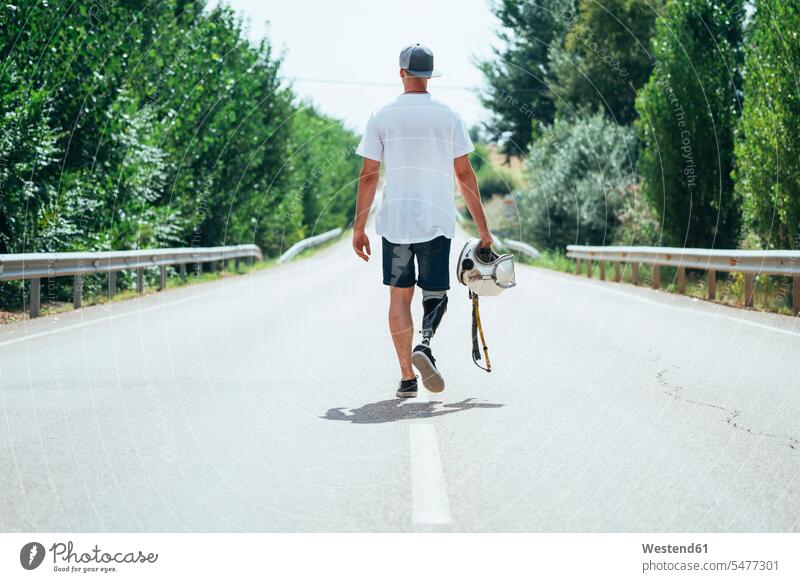 Young man with leg prosthesis walking along the road with a helmet T- Shirt t-shirts tee-shirt go going hold seasons summer time summertime summery free time