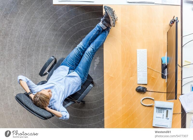 Top view of woman relaxing in chair at desk in office chairs offices office room office rooms relaxed relaxation desks females women workplace work place
