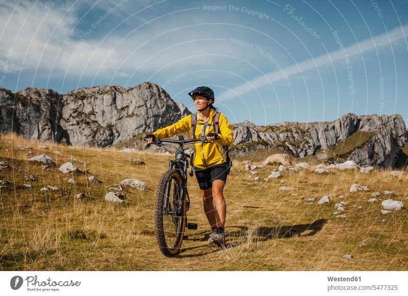 Mid adult woman holding bicycle while against mountain at Somiedo Natural Park, Spain color image colour image outdoors location shots outdoor shot