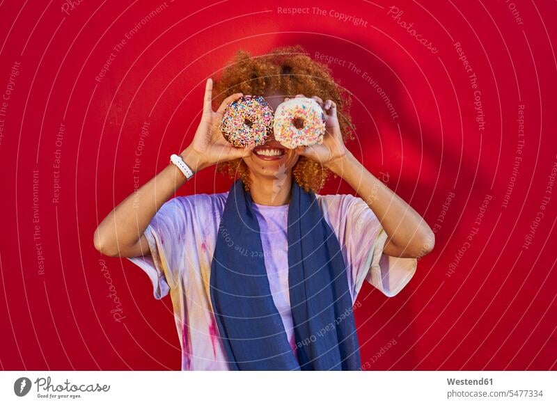 Playful woman holding two donuts in front of her eyes human human being human beings humans person persons African black black ethnicity coloured adult grown-up