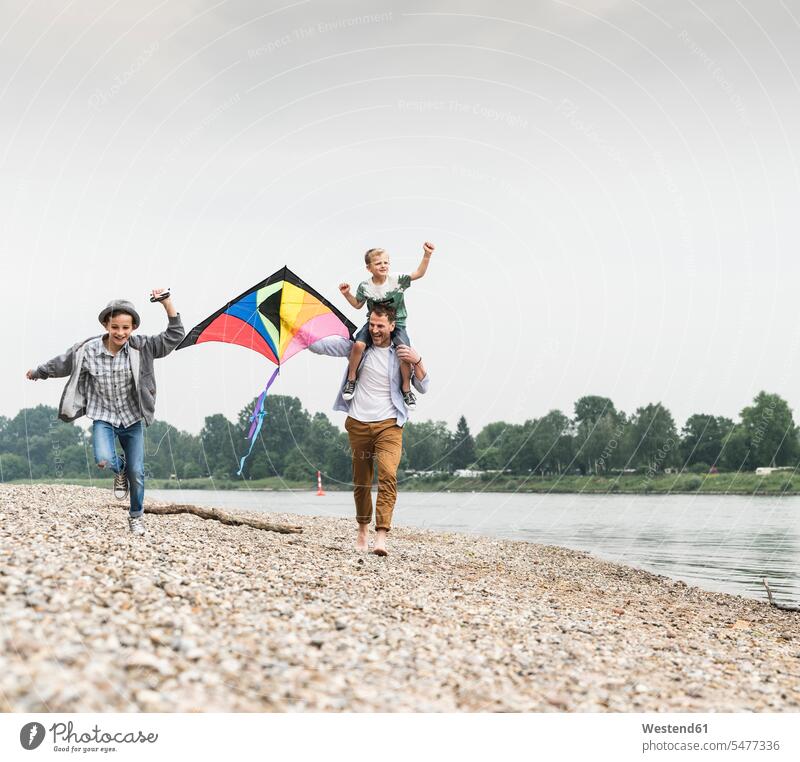 Happy father with two sons flying kite at the riverside manchild manchildren happiness happy running River Rivers kiteflying kite flying pa fathers daddy dads