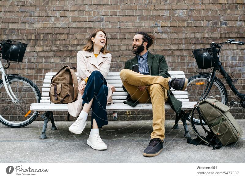 Happy couple sitting on a bench next to e-bikes talking E-Bike Electric bicycle Electric Bike happiness happy speaking Seated bicycles twosomes partnership