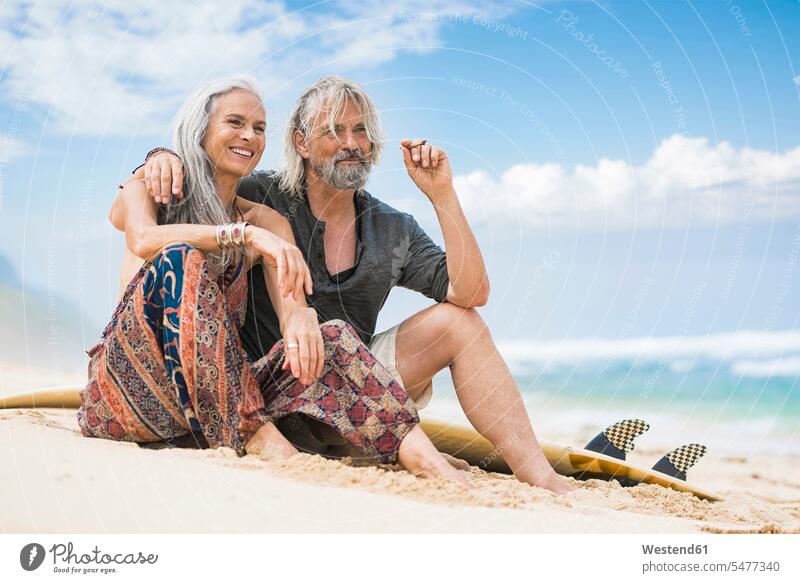 Portrait of senior hippie couple with surfboard relaxing on the beach relaxation twosomes partnership couples sand sandy surfboards Hippy hippies