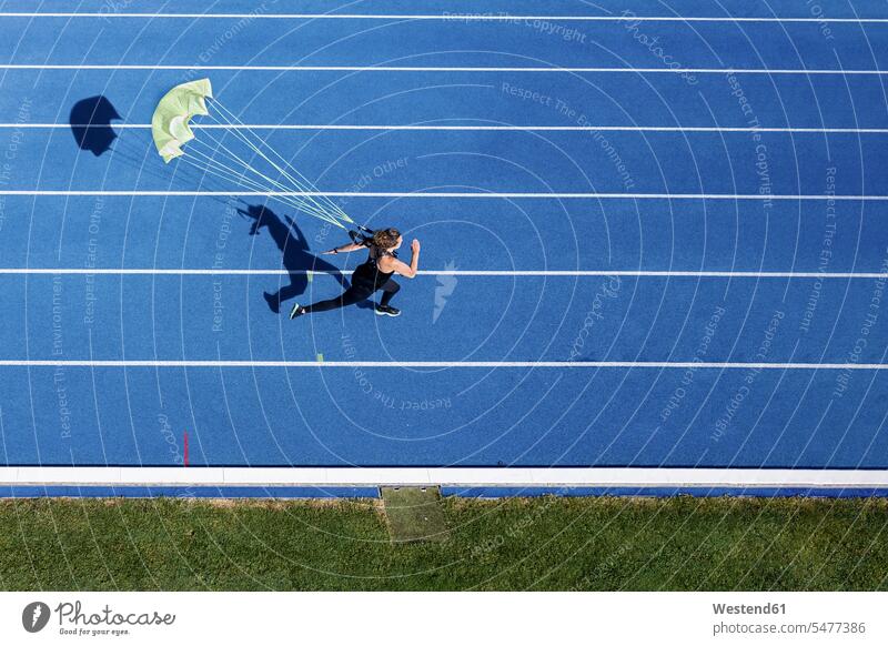 Top view of female runner with parachute on tartan track Brolly umbrellas exercise practising train training colour colours apace quick rapidity rapidness