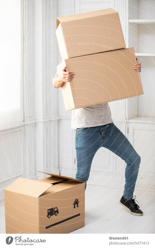 Unrecognizable man carrying cardboard boxes in new home apartment flats apartments at home males Cardboard Carton carton Cardboards cartons moving house move