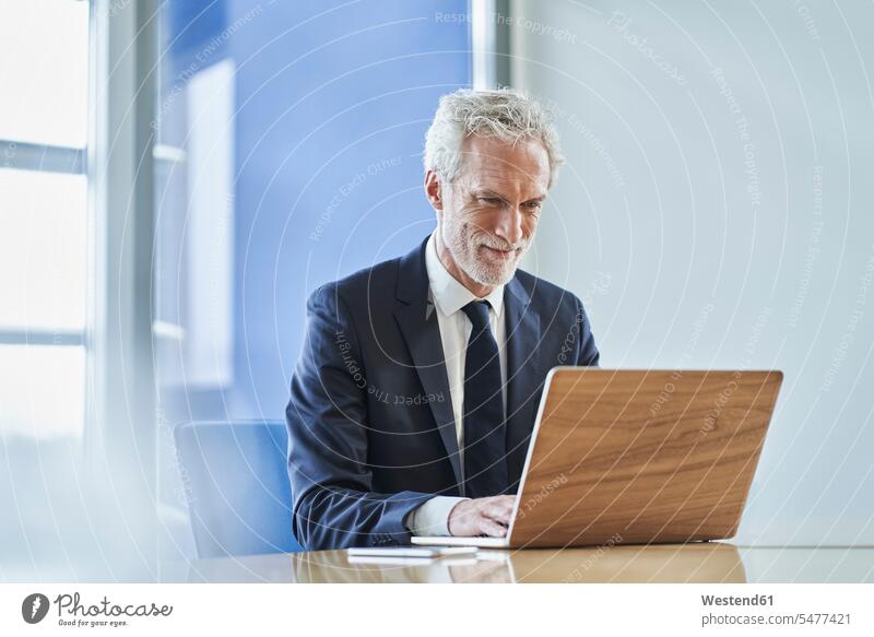 Confident businessman using laptop at desk in office Occupation Work job jobs profession professional occupation business life business world business person