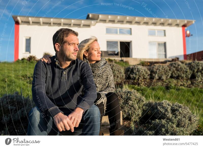 Couple sitting in the sun, in front of their house couple twosomes partnership couples happiness happy holiday home holiday homes holiday lodge holiday lodges