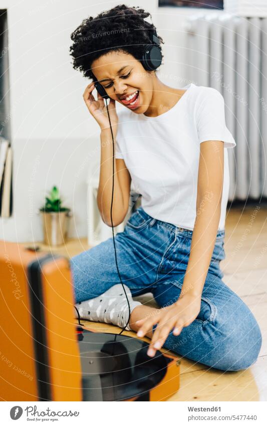 Young woman sitting on grounf listening music from record player, using headphones sitting on ground Sitting On The Floor Sitting On Floor turntable