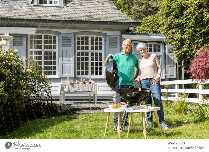Happy senior couple having a barbecue in garden of their home Tables barbecue grill barbecue grills Barbeque Grill Eye Glasses Eyeglasses specs spectacles