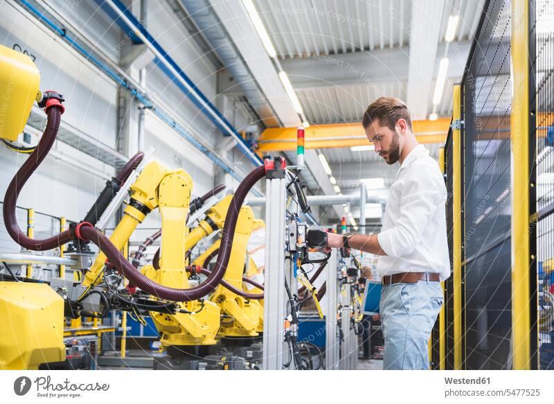Side view of confident robotics expert examining machinery in factory color image colour image Germany indoors indoor shot indoor shots interior interior view