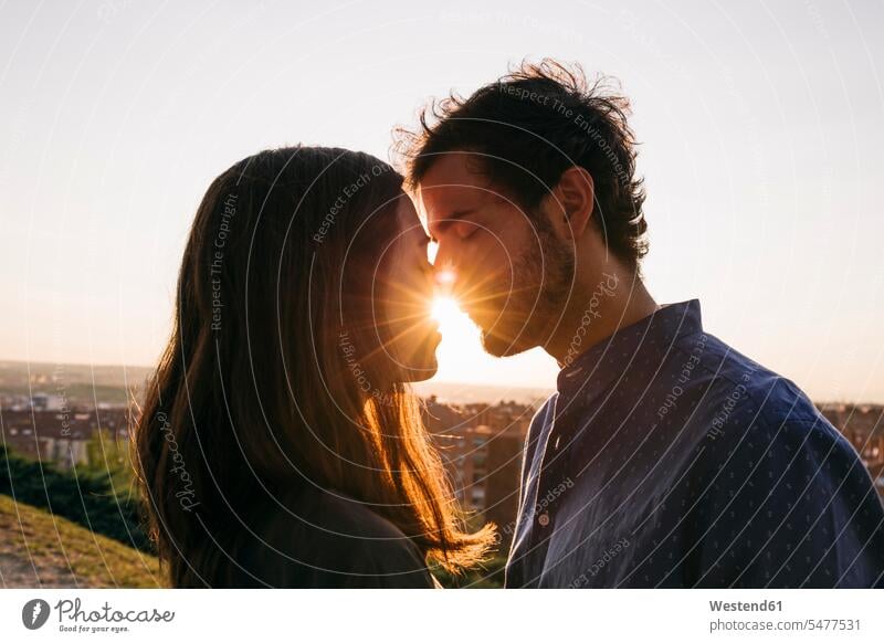 Man and woman kissing while standing against clear sky color image colour image outdoors location shots outdoor shot outdoor shots sunset sunsets sundown