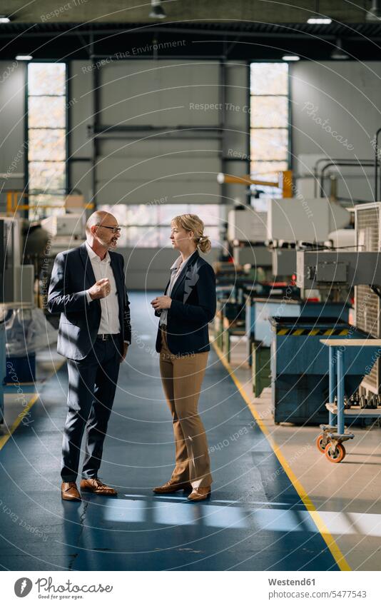 Businessman and businesswoman talking in a factory business life business world business person businesspeople associate associates business associate
