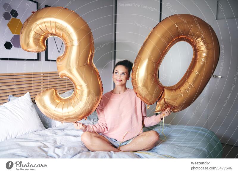 Happy woman holding golden balloons at birthday morning females women happiness happy smiling smile bed beds alone solitary solo Birthday Birthday Celebration