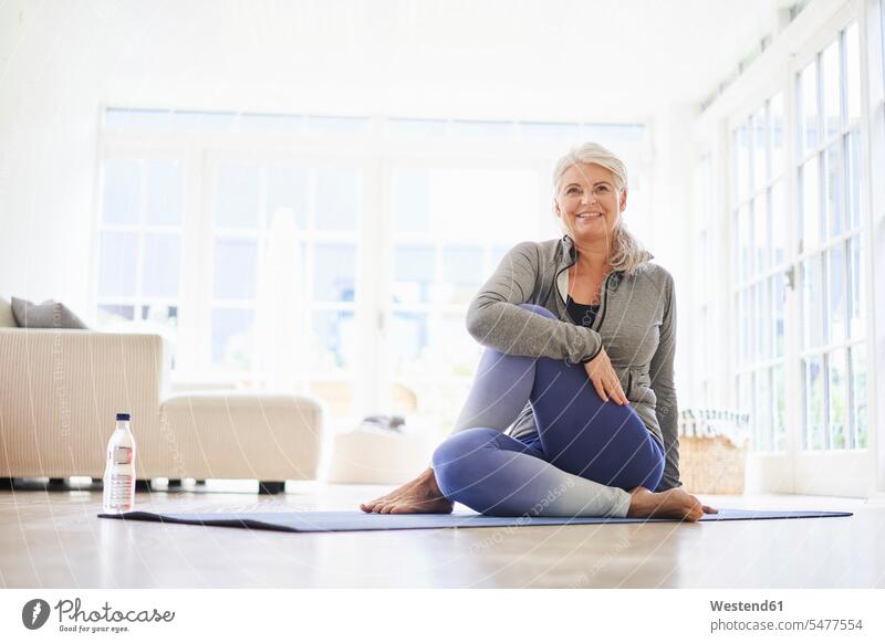 Smiling senior woman doing exercise on mat in living room color image colour image indoors indoor shot indoor shots interior interior view Interiors day