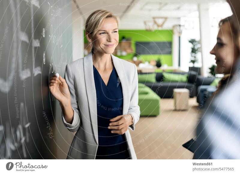 Businesswoman brainstorming at blackboard in office human human being human beings humans person persons caucasian appearance caucasian ethnicity european Group