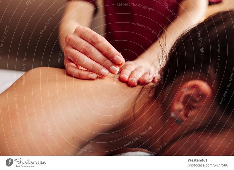 Physiotherapist inserting needle on back while applying dry needling therapy color image colour image indoors indoor shot indoor shots interior interior view