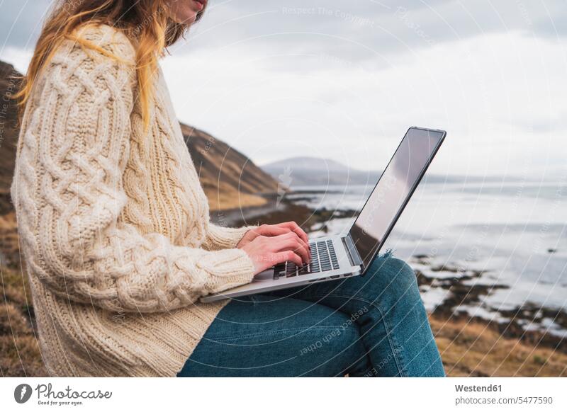 Iceland, woman using laptop at the coast coastline shoreline Laptop Computers laptops notebook females women computer computers Adults grown-ups grownups adult