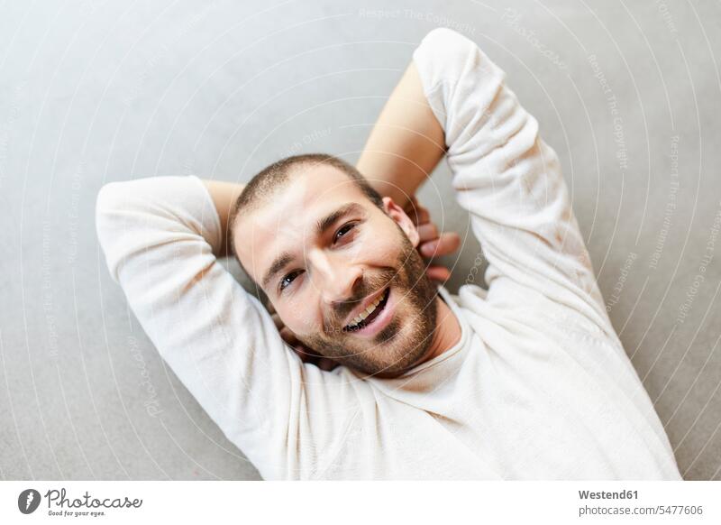 Portrait of happy young man lying on the floor resting floors leisure free time leisure time Fun having fun funny balance balanced break hands behind head