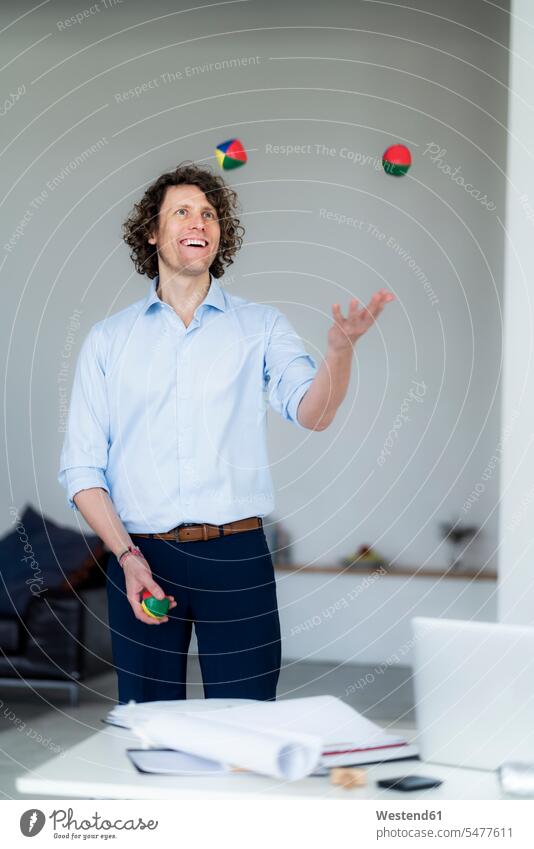 Laughing businessman juggling balls in his office playing happiness happy juggle Office Offices laughing Laughter Businessman Business man Businessmen