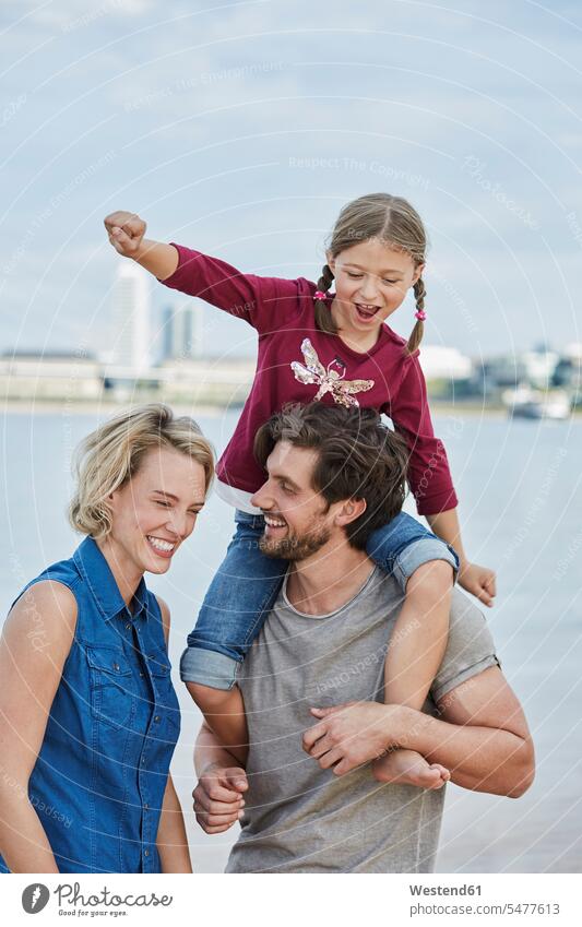 Germany, Duesseldorf, happy family with daughter at Rhine riverbank happiness riverside families Affection Affectionate daughters River Rivers water's edge