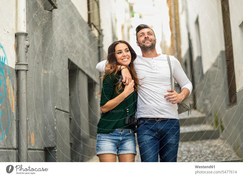 Happy tourist couple walking in the city tourists going happiness happy town cities towns twosomes partnership couples tourism touristic outdoors outdoor shots