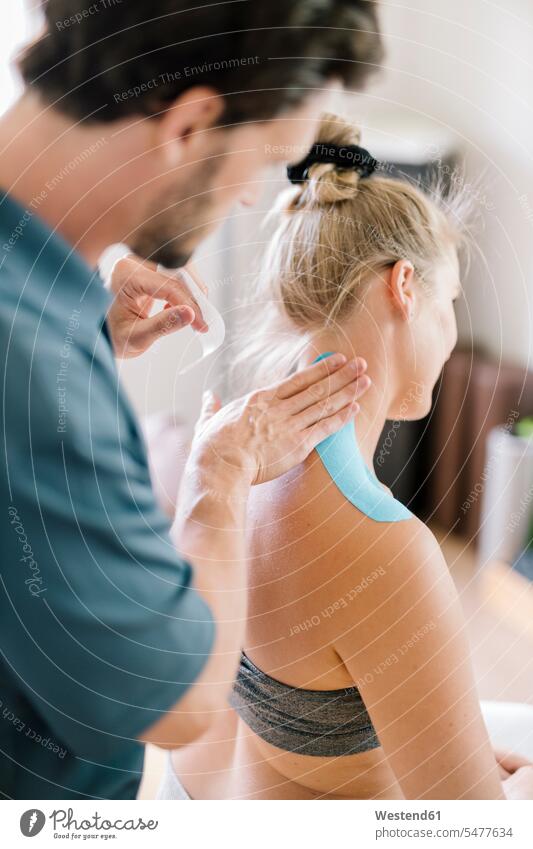 Physiotherapist applying therapeutic tape on patient's neck Occupation Work job jobs profession professional occupation supporting indoor indoor shot