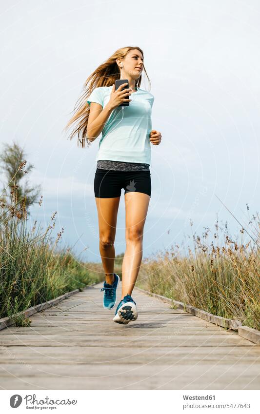 Female jogger running on wooden walkway, listening music human human being human beings humans person persons caucasian appearance caucasian ethnicity european
