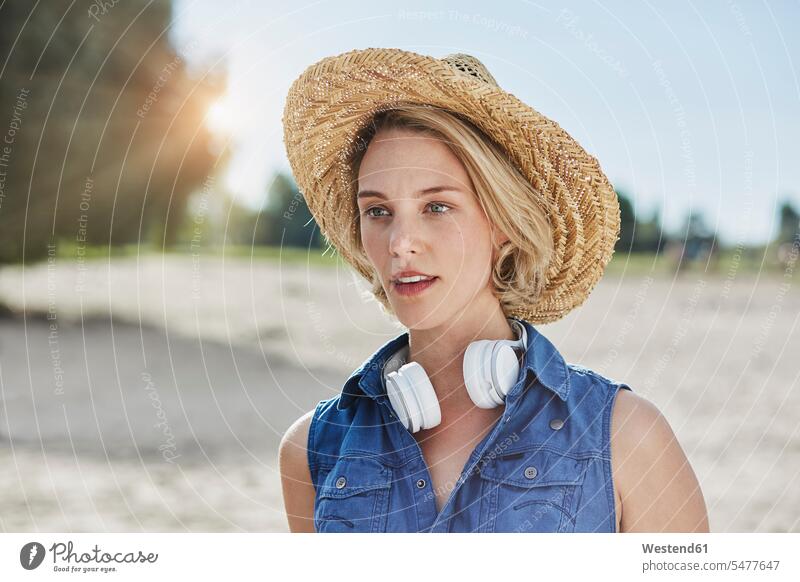 Portrait of young woman with headphones and straw hat on the beach headset portrait portraits beaches straw hats females women Adults grown-ups grownups adult