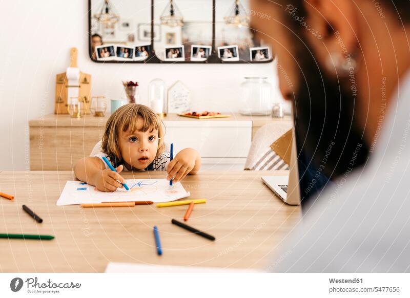 Cute girl looking at father while painting on paper in dining room color image colour image indoors indoor shot indoor shots interior interior view Interiors