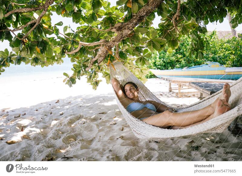 Philippines, Palawan, Mangenguey Island, Busuanga, woman lying in hammock at the beach Traveller Travellers Travelers hammocks laying down lie lying down