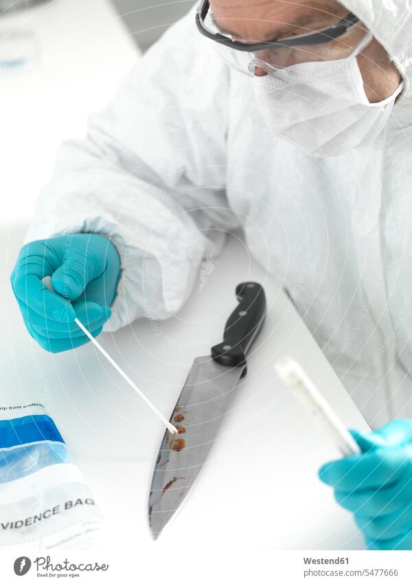 Forensic scientist taking DNA evidence from a blood smeared knife (value=0) human human being human beings humans person persons caucasian appearance