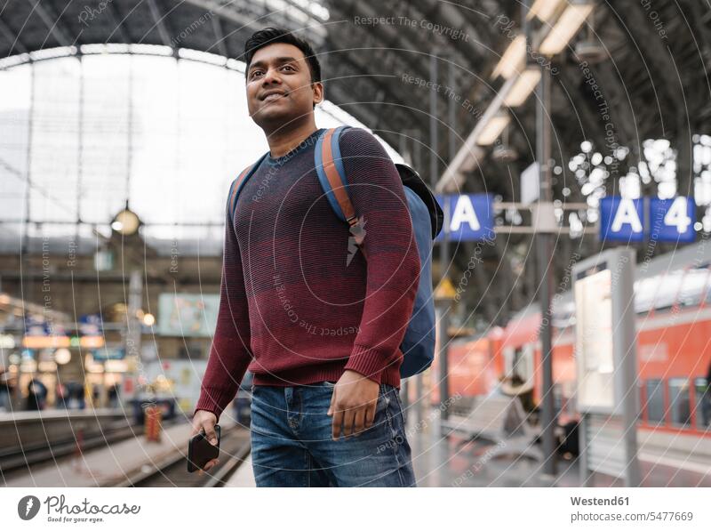Man with smartphone waiting for the train at the train station touristic tourists back-pack back-packs backpacks rucksack rucksacks jumper sweater Sweaters
