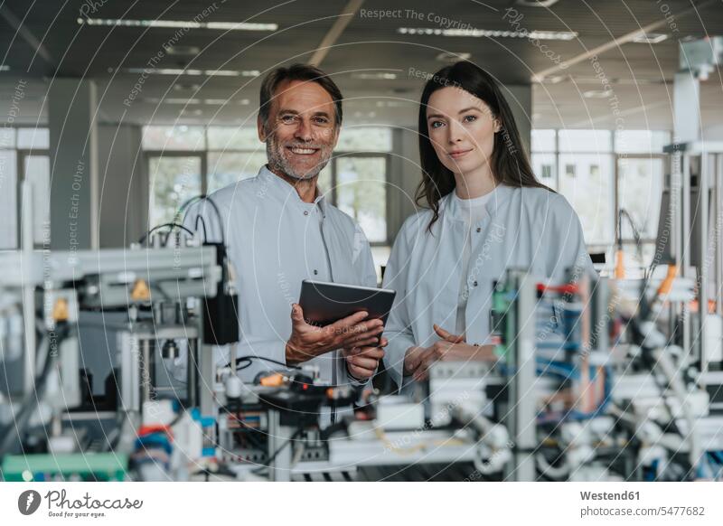 Confident engineers standing by machinery in laboratory color image colour image indoors indoor shot indoor shots interior interior view Interiors scientist