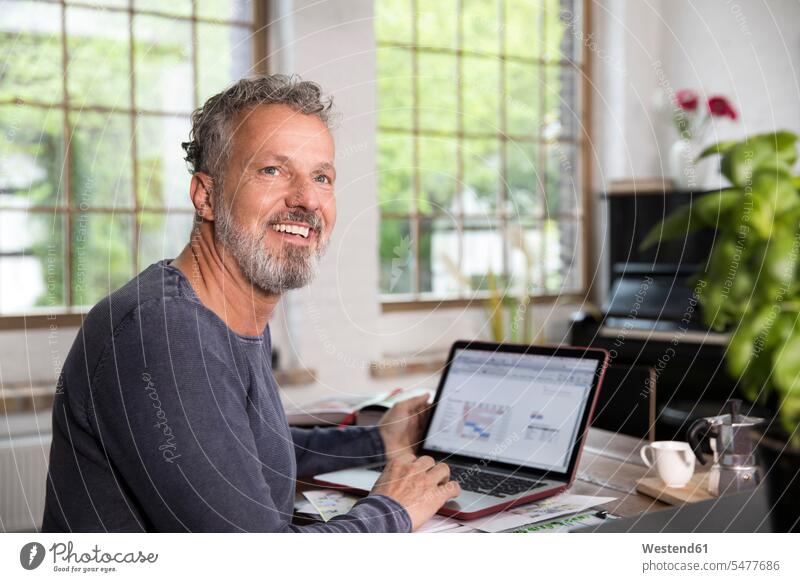 Mature man working in his home office at a loft apartment working from home home business using laptop using a laptop Using Laptops lofts Laptop Computers