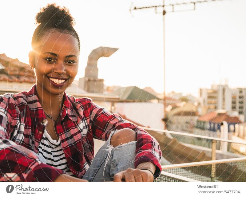 Portrait of happy young woman on rooftop at sunset relax relaxing smile Seated sit in the evening Late Evening seasons summer time summertime summery relaxation