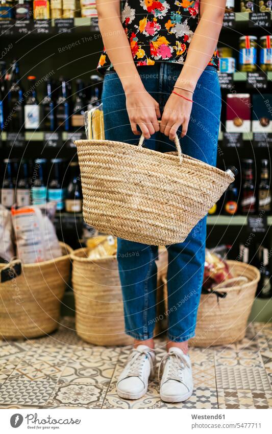 Low section of customer holding basket in a store woman females women female customer shop baskets Adults grown-ups grownups adult people persons human being
