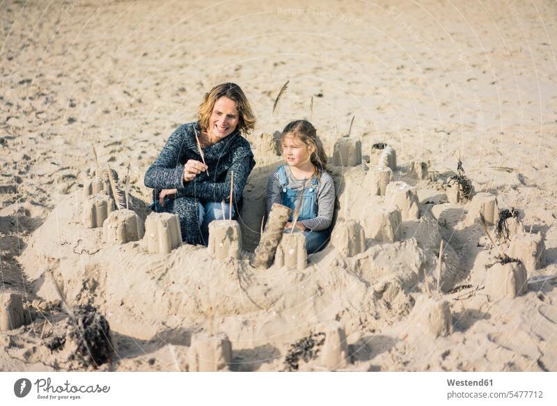 Mother and daughter building a sandcastle on the beach sand castle daughters mother mommy mothers ma mummy mama playing sandy beaches mature woman mature women