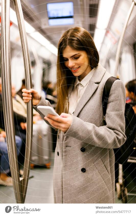 Spain, Barcelona, young businesswoman using cell phone in underground train Smartphone iPhone Smartphones females women businesswomen business woman